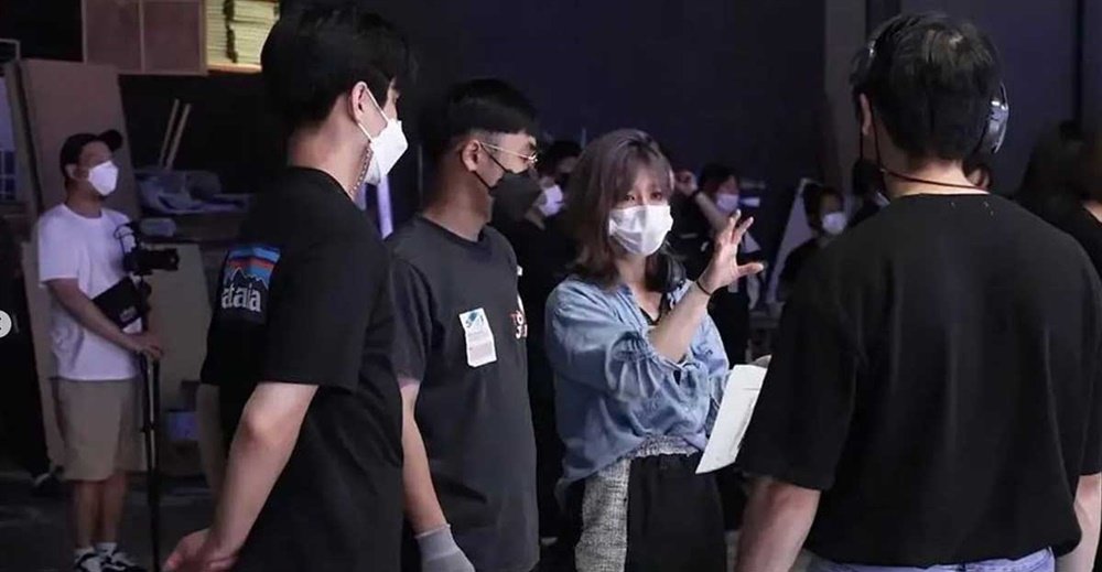 Retrato do diretora Yoon Seung-rim durante uma gravação ou entrevista, observando um monitor de vídeo no set.